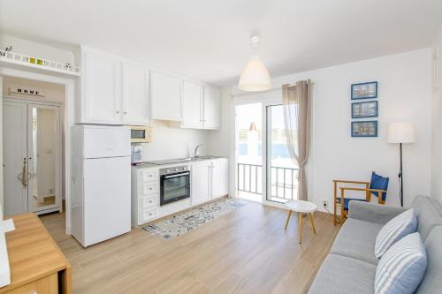 Es GrauFantástico apartamento frente al mar en Menorca的厨房以及带白色橱柜和沙发的客厅。