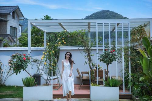 德清莫干山雅泉山居的身着白色衣服的女人站在种有盆栽植物的门廊上