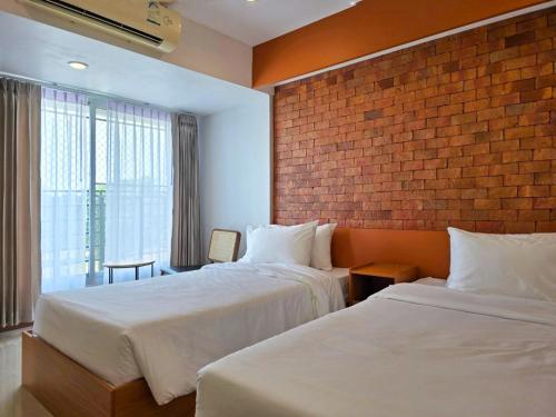 彭世洛Wangkaew Hotel的酒店客房带两张床和砖墙