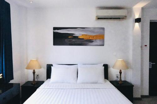 胡志明市Nicecy Hotel - Yersin Street的一间卧室配有一张带白色床单和两盏灯的床。