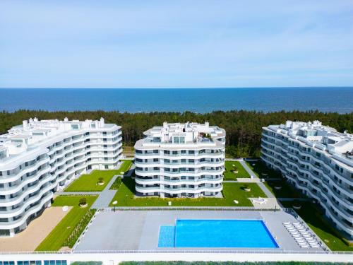 洛格沃Rogowo Pearl City Apartments的海滨三栋带游泳池的公寓楼