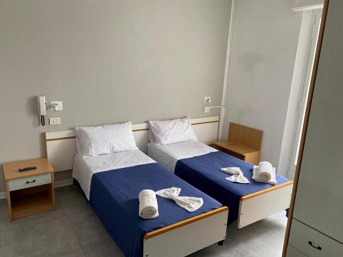 里米尼HOTEL PICCARI Nuova gestione的两张位于酒店客房的床,配有毛巾