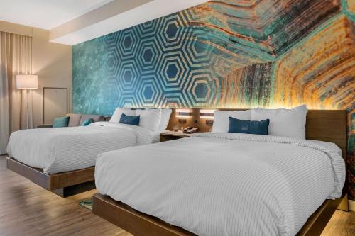 圣徒皮特海滩Cambria Hotel St Petersburg-Madeira Beach Marina的两张位于酒店客房的床铺,配有壁画