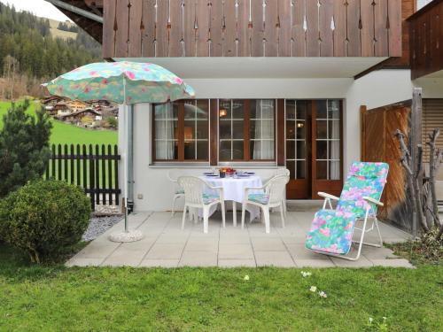 茨韦西门Apartment Chalet Simmental P-3 by Interhome的庭院配有桌椅和遮阳伞。
