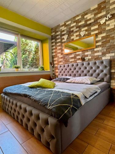 格涅兹诺Apartament "Love Island" z Jacuzzi SPA dla Dwojga的砖墙客房内的一张大床