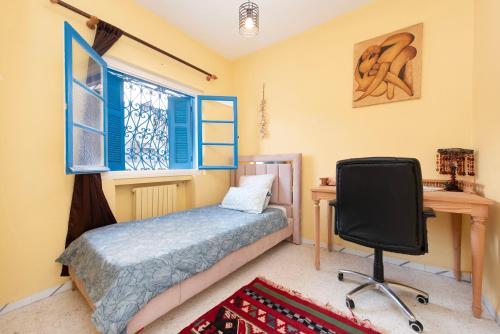 西迪·布·赛义德Coup de cœur à Sidi Bou Said的一间卧室配有一张床、一张桌子和一把椅子
