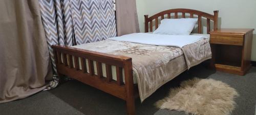 利隆圭Cozy Paradise Apartment的一间卧室配有一张木床、枕头和一张桌子