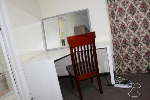 利隆圭Cozy Paradise Apartment的一张椅子,坐在一张桌子前,带镜子