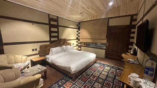 锡卡都Qayam Skardu的一间卧室配有一张床、一张沙发和一把椅子