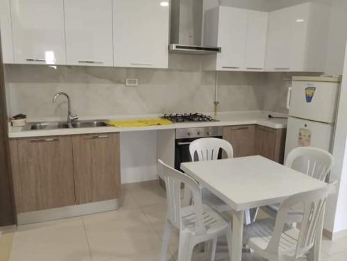 El AhmarRésidence Sousse的厨房配有白色的桌椅和水槽