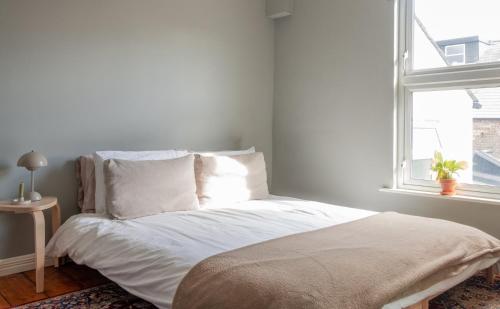 都柏林GuestReady - Victorian redbrick in heart of Dublin的一间卧室配有一张带白色床单的床和一扇窗户。