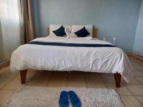 KakamegaHotel Illusions的床上铺有2条蓝色拖鞋