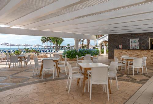 萨尔雷VOI Praia de Chaves Resort的一个带桌子和白色椅子的庭院和大海
