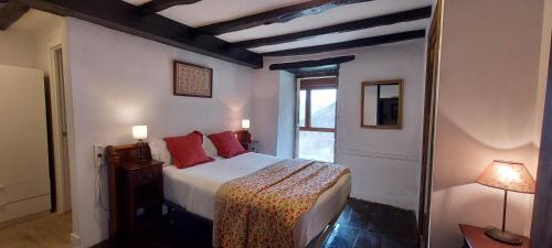 埃利松多CASA RURAL Urruska的一间卧室配有一张带红色枕头的床和一扇窗户