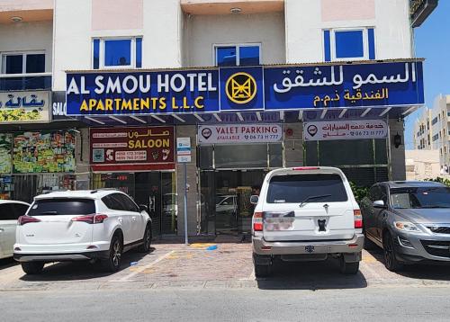 阿吉曼Al Smou Hotel Apartments - MAHA HOSPITALITY GROUP的两辆白色汽车停在大楼前