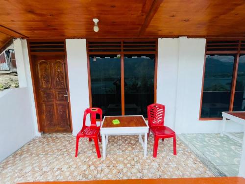 图克图克Elsina guest house的庭院配有2把红色椅子和桌子