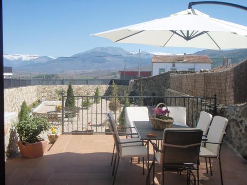 La CarreraCASA RURAL SANDRA的庭院配有桌椅和遮阳伞。