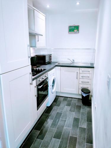 OssettButterfly Apartment的厨房配有白色橱柜和一台洗衣机