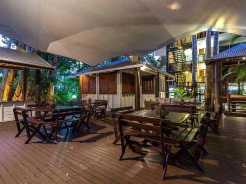 棕榈湾礁石宁静棕榈湾酒店的一间在甲板上配有木桌和椅子的餐厅