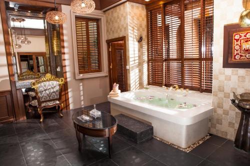 拉迈Ammatara Pura Pool Villa的带浴缸、椅子和桌子的浴室
