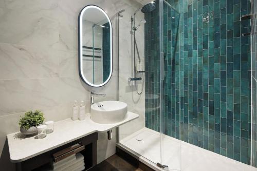 格拉斯哥Leonardo Royal Hotel Glasgow的浴室配有盥洗盆和带镜子的淋浴
