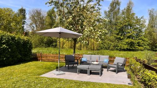 因塞尔波埃尔Haus Sansibar auf Poel mit Sauna& Kamin, ruhiger Garten-700m vom Strand!的庭院配有桌椅和遮阳伞。