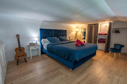 圣吉尔-克鲁瓦德维Villa Notre Dame : Vue sur port, 2min Grande plage的一间卧室配有一张蓝色的床和吉他