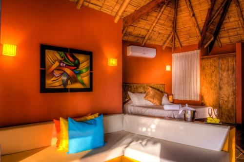 卡诺阿斯德蓬萨尔Yemaya Boutique Hotel en Canoas的一间设有床铺的卧室,位于一个拥有橙色墙壁的房间