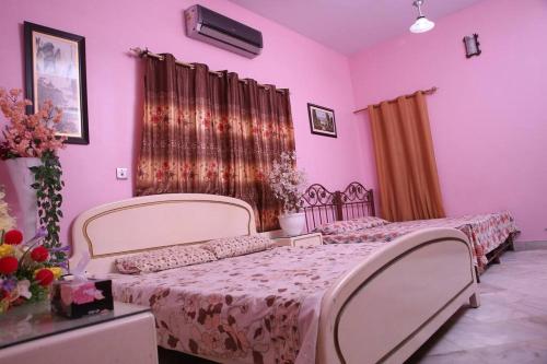 卡拉奇Regal Palace Gulshan Nipa的一间卧室设有两张床,墙壁粉红色