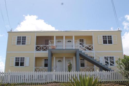 圣约翰斯Petals Lovely Beach Villa的前面有白色围栏的黄色房子
