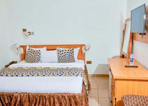 拉各斯Definite Destiny Hotel by YOTRAD的配有一张床和一张书桌的酒店客房