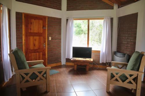 普埃洛湖Chacra confluenza的客厅配有两把椅子和电视