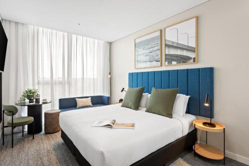 WooloowareQuest Woolooware Bay的酒店客房设有一张大床和蓝色床头板