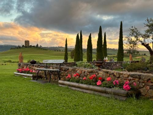 ContignanoDimora Buonriposo Pienza Country House的一座带石墙、桌子和鲜花的花园