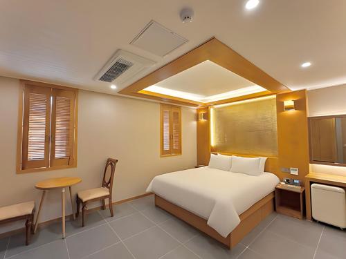 束草市Sokcho Mir Hotel的卧室配有1张床、1张桌子和1把椅子