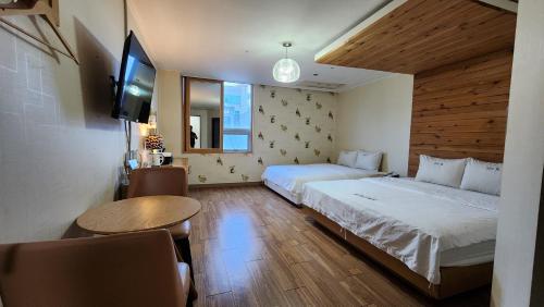 金海市Gimhae Business Hotel K的一间卧室设有两张床、一台电视和一张桌子