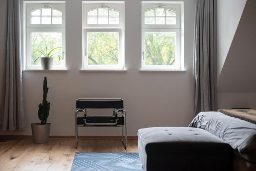 莱比锡Apartment mit Parkblick & Massagestuhl的一间卧室设有三扇窗户和一把椅子
