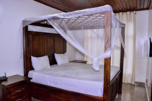 基加利The Keza Hotel的一间卧室配有一张木床和天篷