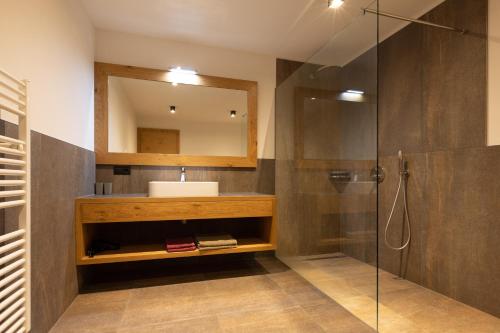 蒂鲁罗普拉提霍夫公寓的浴室配有盥洗盆和带镜子的淋浴