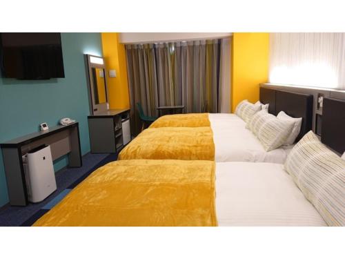 名户Green Rich Hotel Okinawa Nago - Vacation STAY 49879v的两张床位于带黄色墙壁的酒店客房