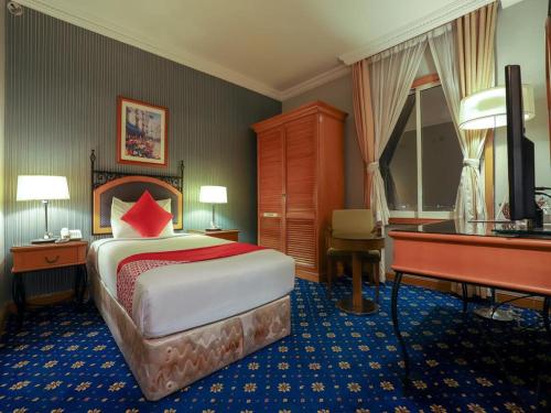 富查伊拉City Plaza Hotel的酒店客房带一张床和一架钢琴