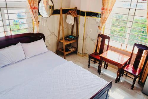 惹岛Hoa Bien Motel的一间卧室配有一张床、两把椅子和窗户