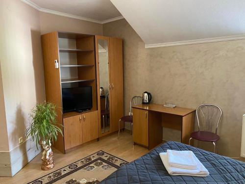 LalovoHotel Zoloti Vorota的一间卧室配有一张床、一张书桌和一台电视