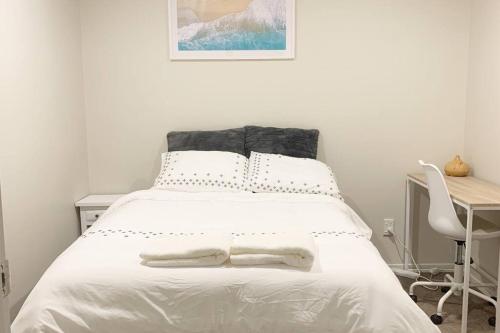 奥克兰Serene 5-Bedroom Papakura Home的一间卧室配有一张带白色床单的床和一张书桌。