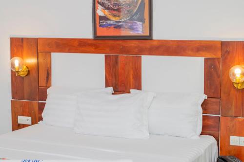 科托努Hotel BKBG Benin的一张带木制床头板的床,上面有一张图画