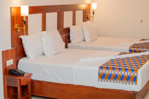 科托努Hotel BKBG Benin的一张位于酒店客房的两张床,配有一张桌子上的电话