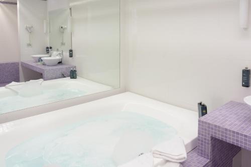 科森扎Ariha Hotel Cosenza的带浴缸、水槽和镜子的浴室