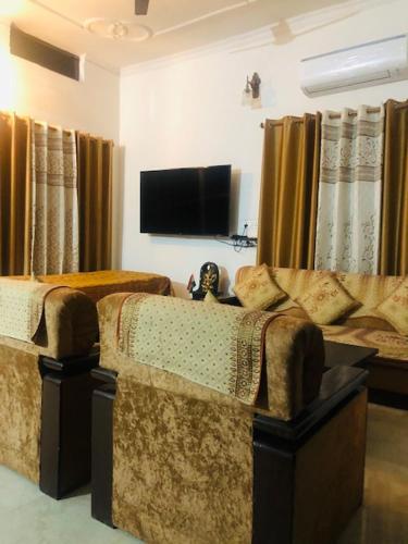 瓦拉纳西Tattva Luxurious Apartment的客厅配有2把椅子和平面电视