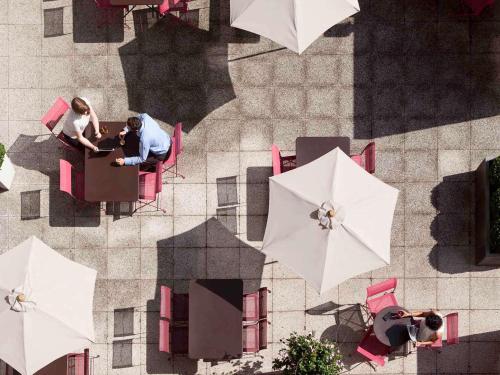 鲁昂鲁昂诺曼底诺富特套房酒店的一群人坐在桌子上,拿着雨伞