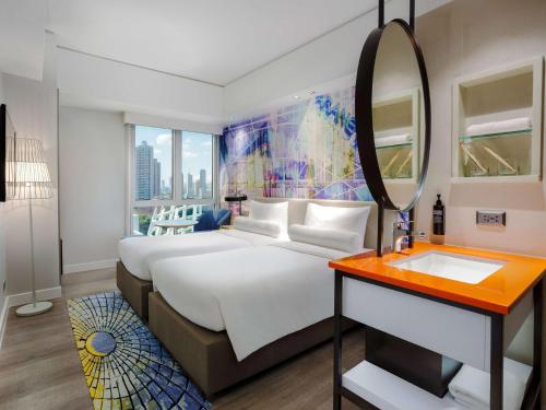 马尼拉ibis Styles Manila Araneta City的一间卧室配有一张大床和镜子